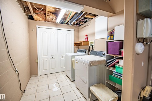 Laundry area featuring tiled flooring, a built-in wall shelf, and bifolds doors - 3920 35A Avenue, Red Deer, AB - Indoor Photo Showing Laundry Room