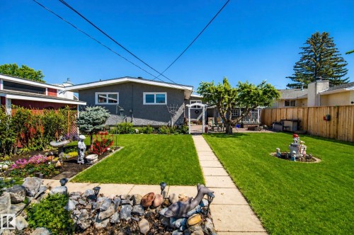 Expansive backyard featuring a central concrete walkway, mature trees, and a decorative garden arbor - 3920 35A Avenue, Red Deer, AB - Outdoor