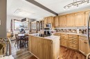Kitchen featuring extensive light wood cabinetry, integrated appliances, a central island with a cooktop, and contrasting wood-finish flooring - 3920 35A Avenue, Red Deer, AB  - Indoor Photo Showing Kitchen 