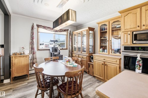 Kitchen and dining area featuring wood-finish flooring, light wood cabinetry, a built-in microwave, and a double wall oven - 3920 35A Avenue, Red Deer, AB - Indoor