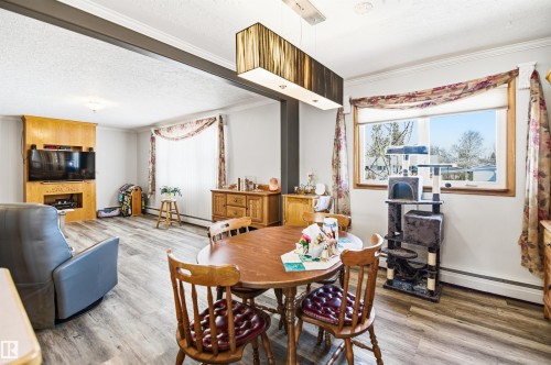 Open-concept dining area with wood-finish flooring, a contemporary linear chandelier, and a large window - 3920 35A Avenue, Red Deer, AB - Indoor
