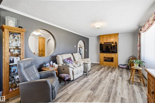 Living space featuring wood-finish flooring, a wall-mounted entertainment center with built-in shelving, crown molding, and a circular wall cut-out detail - 3920 35A Avenue, Red Deer, AB - Indoor Photo Showing Living Room