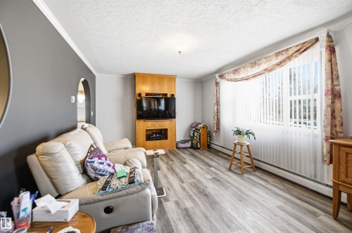 Spacious room featuring wood-finish flooring and a multi-pane bay window - 3920 35A Avenue, Red Deer, AB - Indoor With Fireplace