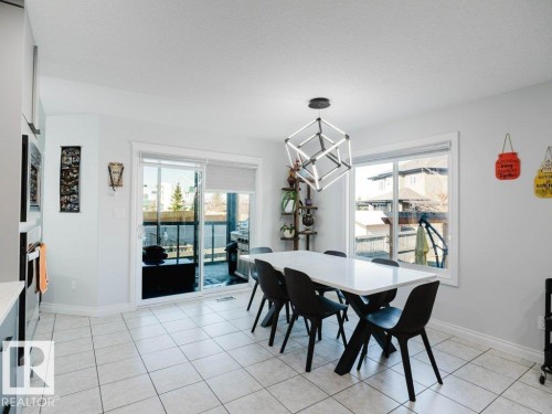 Bright dining area with white tile flooring and a modern geometric pendant light fixture - 5701 Rue Eaglemont, Beaumont, AB - Indoor Photo Showing Dining Room