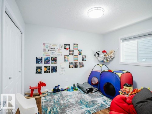 Playroom - Bright room featuring wood-finish flooring, a double-door closet, a large window, and a flush-mount ceiling light - 5701 Rue Eaglemont, Beaumont, AB - Indoor