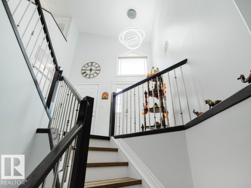 Staircase featuring dark wood handrails and metal balusters - 5701 Rue Eaglemont, Beaumont, AB - Indoor Photo Showing Other Room