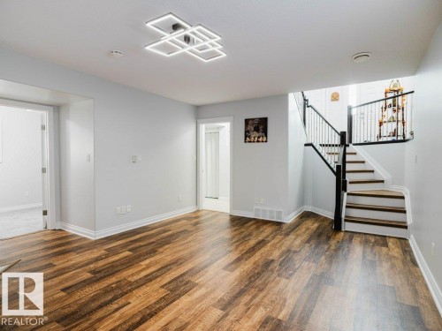 Spacious room featuring wood-finish flooring, white baseboards, and light gray walls - 5701 Rue Eaglemont, Beaumont, AB - Indoor Photo Showing Other Room