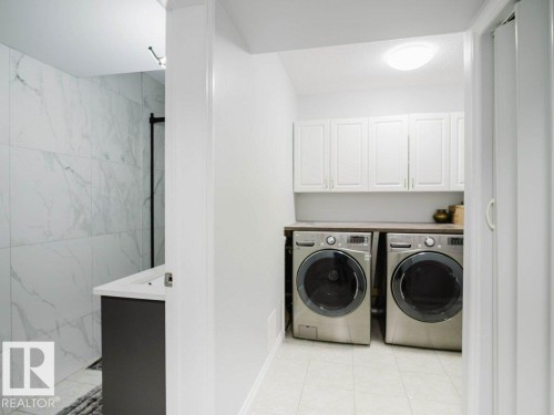 Dedicated laundry area featuring white upper cabinetry and a dark countertop - 5701 Rue Eaglemont, Beaumont, AB - Indoor Photo Showing Laundry Room