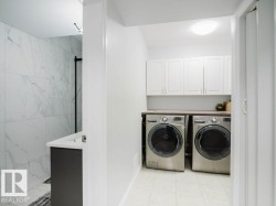 Dedicated laundry area featuring white upper cabinetry and a dark countertop - 