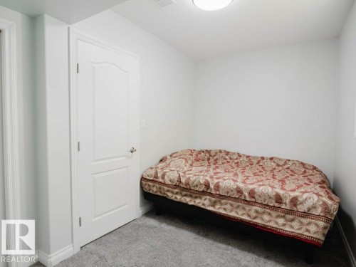 Guest bedroom- Interior room featuring light gray walls, gray carpet, and a white paneled door with a brass-toned knob - 5701 Rue Eaglemont, Beaumont, AB - Indoor Photo Showing Bedroom