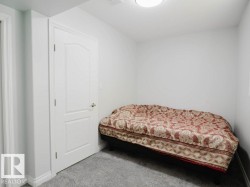 Guest bedroom- Interior room featuring light gray walls, gray carpet, and a white paneled door with a brass-toned knob - 