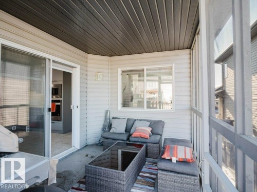 Screened-in porch featuring a dark gray slatted ceiling, light-colored horizontal siding, and a concrete floor - 5701 Rue Eaglemont, Beaumont, AB - Outdoor With Deck Patio Veranda With Exterior