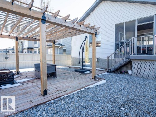 Expansive outdoor living area featuring a wooden pergola, wood-finish decking, and a screened-in porch with direct staircase access - 5701 Rue Eaglemont, Beaumont, AB - Outdoor