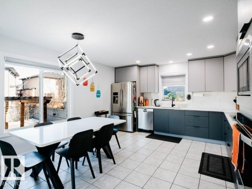Modern kitchen featuring two-tone cabinetry, stainless steel appliances, and a tiled floor - 5701 Rue Eaglemont, Beaumont, AB - Indoor