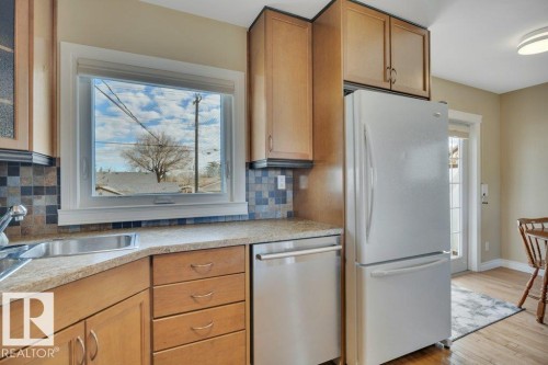 Kitchen featuring a stainless steel sink, light-toned wood cabinetry, a mosaic tile backsplash, and light-colored countertops - 10633 St Gabriel School Road, Edmonton, AB - Indoor Photo Showing Kitchen