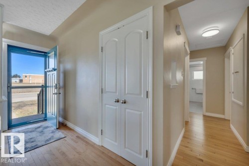 Entryway featuring natural wood-finish flooring, light beige wall paint, white trim, and a white double bifold closet - 10633 St Gabriel School Road, Edmonton, AB - Indoor Photo Showing Other Room