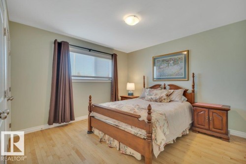 Bedroom featuring wood-finish flooring, a window with blinds, and light green wall paint - 10633 St Gabriel School Road, Edmonton, AB - Indoor Photo Showing Bedroom