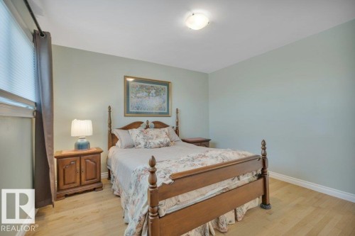 Room featuring light-toned wood-finish flooring, light green walls, a ceiling-mounted light fixture, and white baseboards - 10633 St Gabriel School Road, Edmonton, AB - Indoor Photo Showing Bedroom