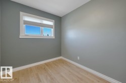 Windowed room with light wood-finish flooring, white baseboards, and a white window frame - 