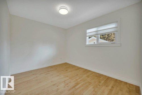Bright room featuring light wood-finish flooring, white walls, and a single window with a privacy shade - 10633 St Gabriel School Road, Edmonton, AB - Indoor Photo Showing Other Room