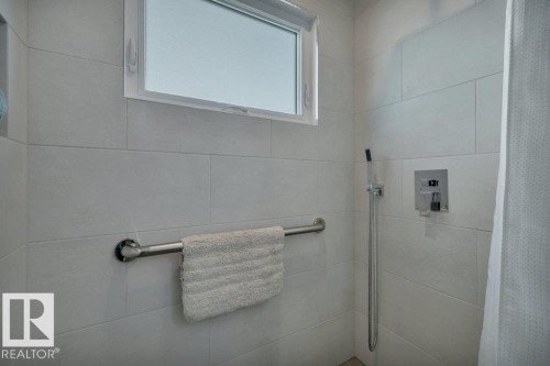 Shower featuring floor-to-ceiling rectangular tile, a horizontal window, and a chrome shower fixture - 10633 St Gabriel School Road, Edmonton, AB - Indoor Photo Showing Bathroom