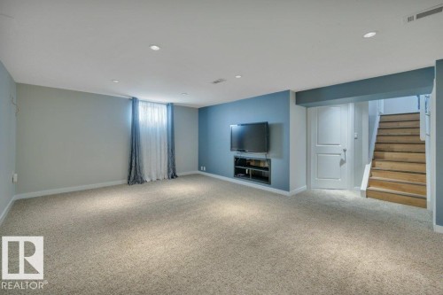 Spacious room featuring light-colored carpeting, recessed ceiling lighting, and a blue accent wall with a built-in media niche - 10633 St Gabriel School Road, Edmonton, AB - Indoor