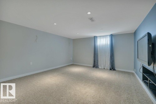 Spacious room featuring light-colored carpeting, recessed lighting, and a window with sheer and patterned drapes - 10633 St Gabriel School Road, Edmonton, AB - Indoor Photo Showing Other Room