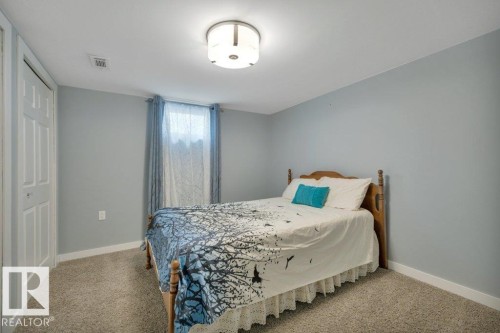 Carpeted room featuring a window with natural light, a bi-fold closet door, light blue wall paint, white trim, and a flush mount ceiling light fixture - 10633 St Gabriel School Road, Edmonton, AB - Indoor Photo Showing Bedroom