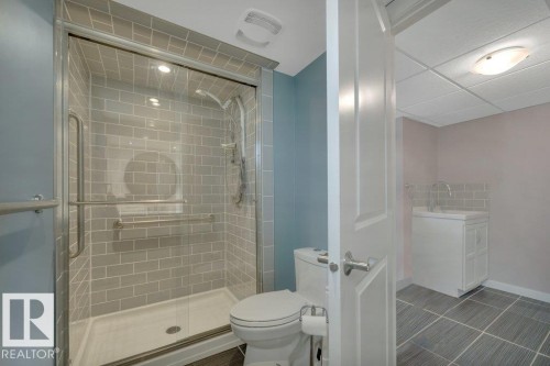 Full bathroom featuring a glass-enclosed shower with subway tile surround, white toilet, and tile flooring - 10633 St Gabriel School Road, Edmonton, AB - Indoor Photo Showing Bathroom