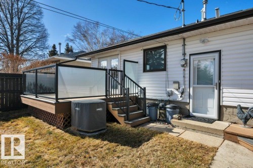 Exterior features include white siding, a raised deck with glass panel railing, and stairs providing access to the yard - 10633 St Gabriel School Road, Edmonton, AB - Outdoor With Deck Patio Veranda With Exterior