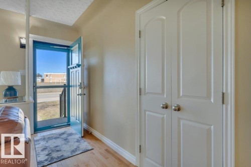 Entryway featuring a blue storm door, light wood-finish flooring, and two white panel doors with brushed nickel hardware - 10633 St Gabriel School Road, Edmonton, AB - Indoor Photo Showing Other Room