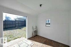 Interior space featuring white walls, plywood flooring, and a single window - 