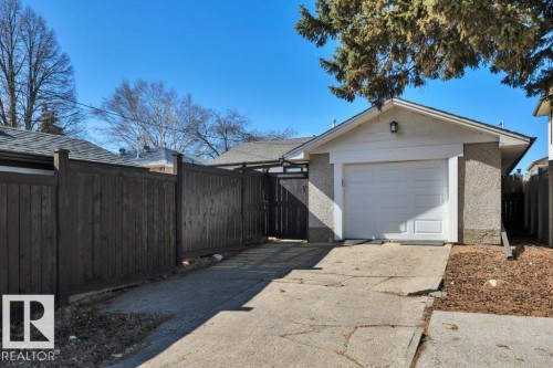 Detached garage with a white overhead door, textured stucco exterior, and an attached outdoor light fixture - 10633 St Gabriel School Road, Edmonton, AB - Outdoor