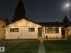 White siding exterior with a dark roof and a teal entry door - 