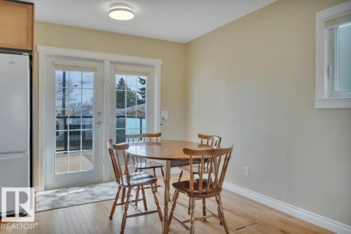Dining area featuring light wood-finish flooring, neutral wall tones, and direct outdoor access via French patio doors with integrated grilles - 10633 St Gabriel School Road, Edmonton, AB - Indoor Photo Showing Dining Room