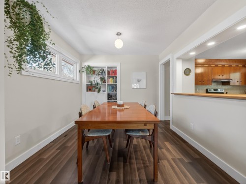 Dining area featuring wood-finish flooring, a built-in shelving unit, and a pass-through opening to the kitchen - 11345 89 Street, Edmonton, AB - Indoor