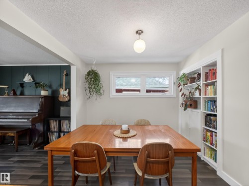 Inviting dining area featuring wood-finish flooring, a white trim window, a ceiling-mounted light fixture, and built-in shelving - 11345 89 Street, Edmonton, AB - Indoor