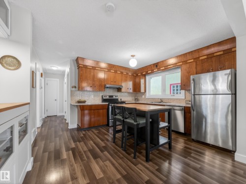 Kitchen featuring wood cabinetry, stainless steel appliances, and wood-finish flooring - 11345 89 Street, Edmonton, AB - Indoor Photo Showing Kitchen