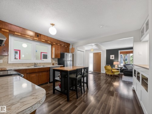 Kitchen featuring wood cabinetry, a mosaic tile backsplash, and a central island with bar seating - 11345 89 Street, Edmonton, AB - Indoor Photo Showing Kitchen With Double Sink