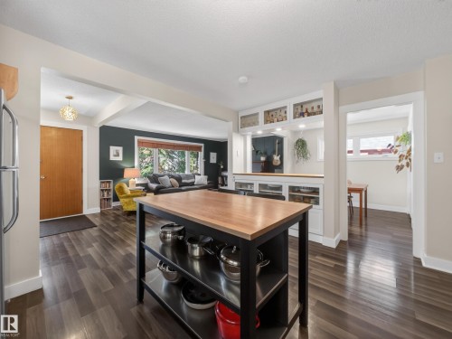 Open-concept interior featuring wood-finish flooring, a kitchen island with a wood countertop, and built-in shelving with display cabinetry - 11345 89 Street, Edmonton, AB - Indoor