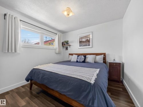 Bedroom featuring wood-finish flooring, white baseboards, and a contemporary ceiling light fixture - 11345 89 Street, Edmonton, AB - Indoor Photo Showing Bedroom