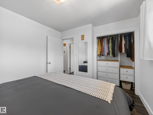 Bedroom featuring recessed closet organization system with drawers and hanging rods, wood-finish flooring, and white walls - 11345 89 Street, Edmonton, AB - Indoor Photo Showing Bedroom