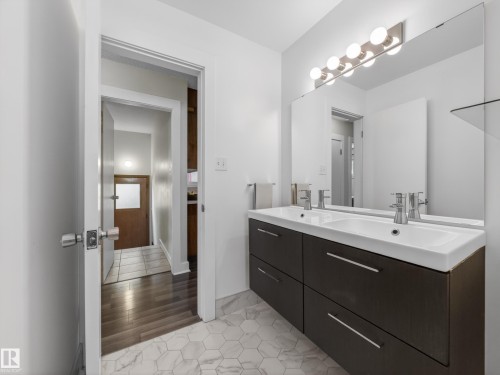 Dual floating vanity with integrated sinks, chrome faucets, and a full-width mirror - 11345 89 Street, Edmonton, AB - Indoor Photo Showing Bathroom