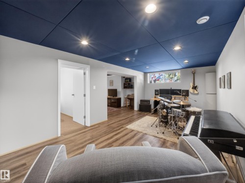 Spacious room featuring wood-finish flooring, light grey walls, and a blue panel ceiling with recessed lighting - 11345 89 Street, Edmonton, AB - Indoor Photo Showing Other Room