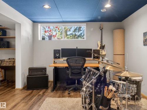 Versatile room featuring wood-finish flooring, a blue acoustic panel ceiling with recessed lighting, and a horizontal window providing natural light - 11345 89 Street, Edmonton, AB - Indoor Photo Showing Office
