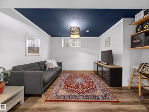 Recreation room featuring wood-finish flooring, white walls, and a deep blue ceiling - 11345 89 Street, Edmonton, AB - Indoor Photo Showing Living Room