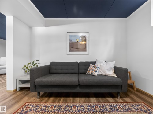 Recessed ceiling with integrated lighting and a dark blue finish, complemented by white walls and wood-finish flooring - 11345 89 Street, Edmonton, AB - Indoor Photo Showing Living Room