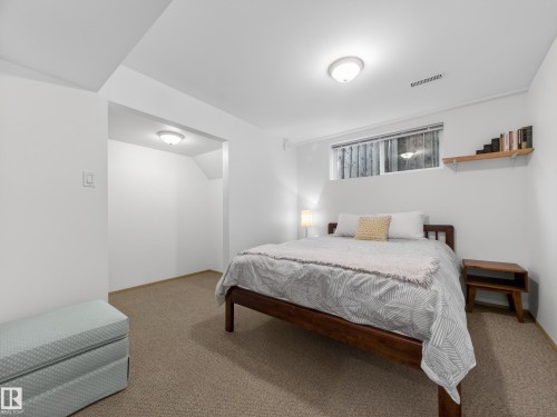 Carpeted room featuring a white ceiling and walls, a built-in shelf, and an egress window - 11345 89 Street, Edmonton, AB - Indoor Photo Showing Bedroom