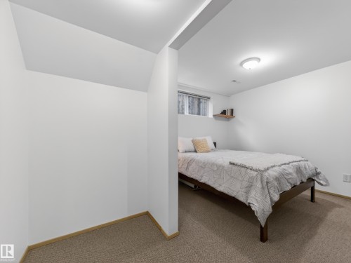Carpeted room with white painted walls and trim, featuring a recessed window, ceiling-mounted light fixture, and a built-in wooden shelf - 11345 89 Street, Edmonton, AB - Indoor Photo Showing Bedroom