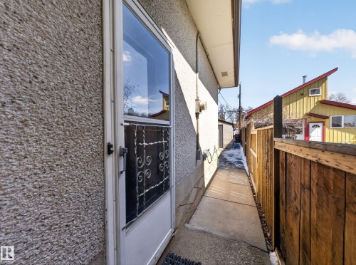 Stucco exterior featuring a full-light storm door with decorative ironwork - 11345 89 Street, Edmonton, AB - Outdoor With Exterior